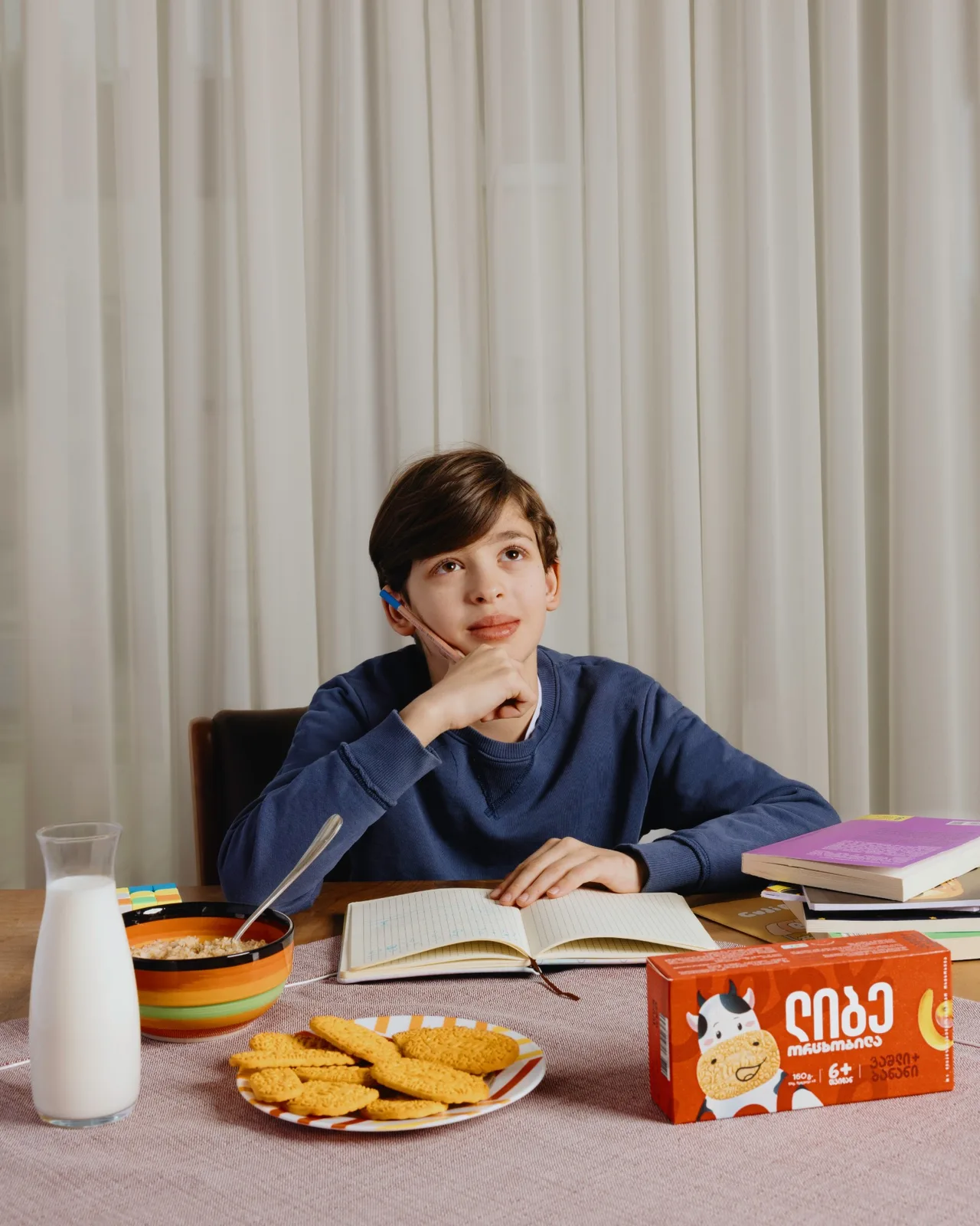 Boy doing homework with milk, cereal and a plate of Liebe biscuits