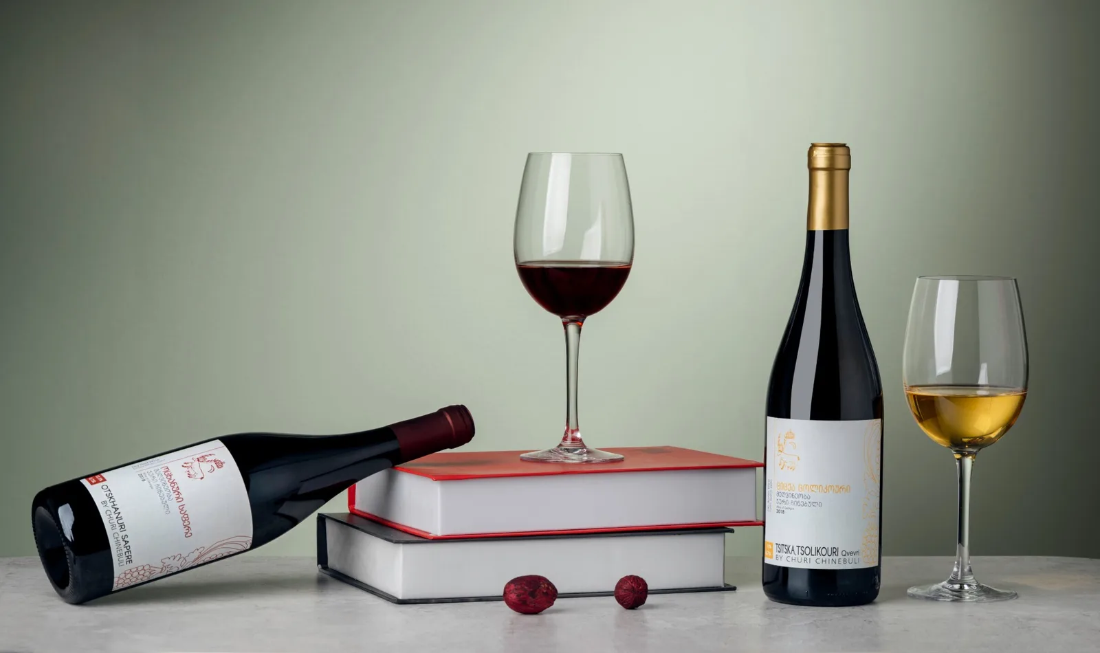 Wine ad: two Churi Chinebuli bottles with glasses of red and amber wine on a stack of books