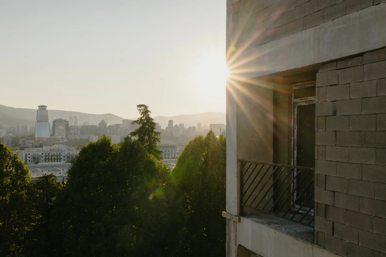 Real estate ad: sunset over the Tbilisi skyline from an unfinished balcony