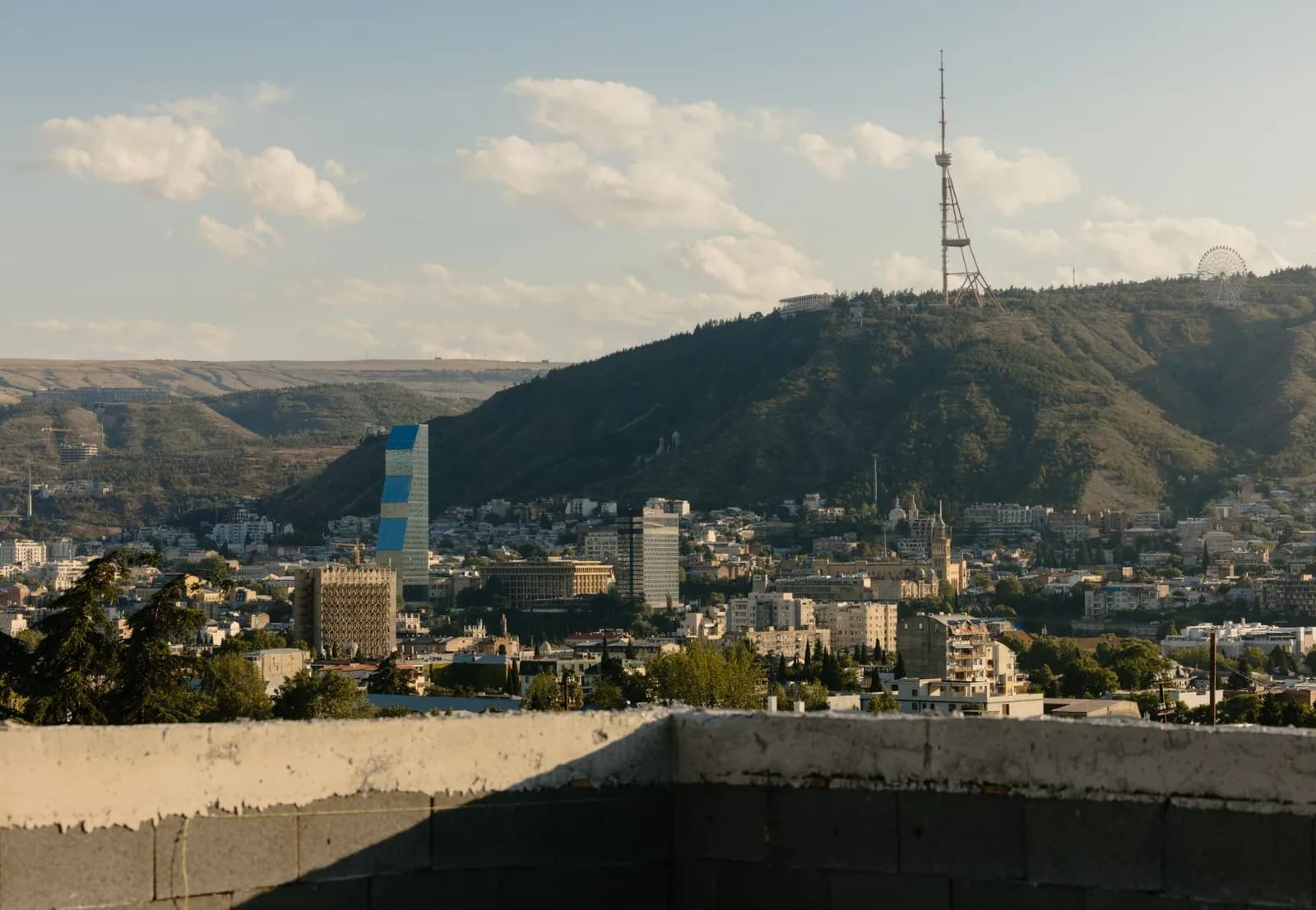Real estate ad: Tbilisi skyline with the TV tower, seen over an unfinished parapet